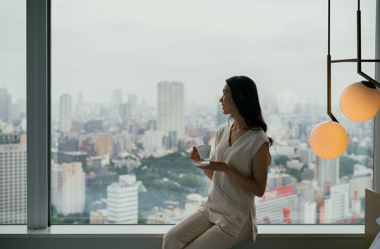 A Person Sitting On A Ledge Overlooking A City