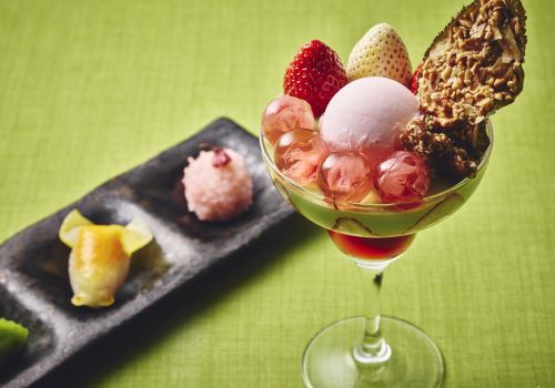 A Glass Of Wine With Fruit And Ice Cream On A Green Surface