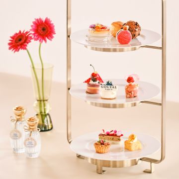 A Glass Table With A Tray Of Cupcakes And Flowers